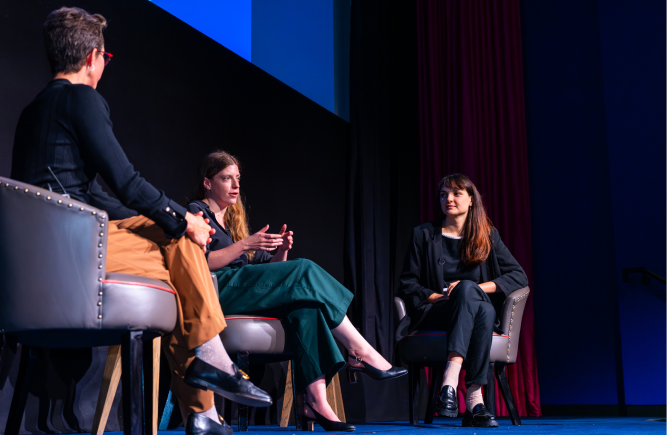 Three women participate in a panel discussion at a Wagestream event, seated in armchairs on stage.
