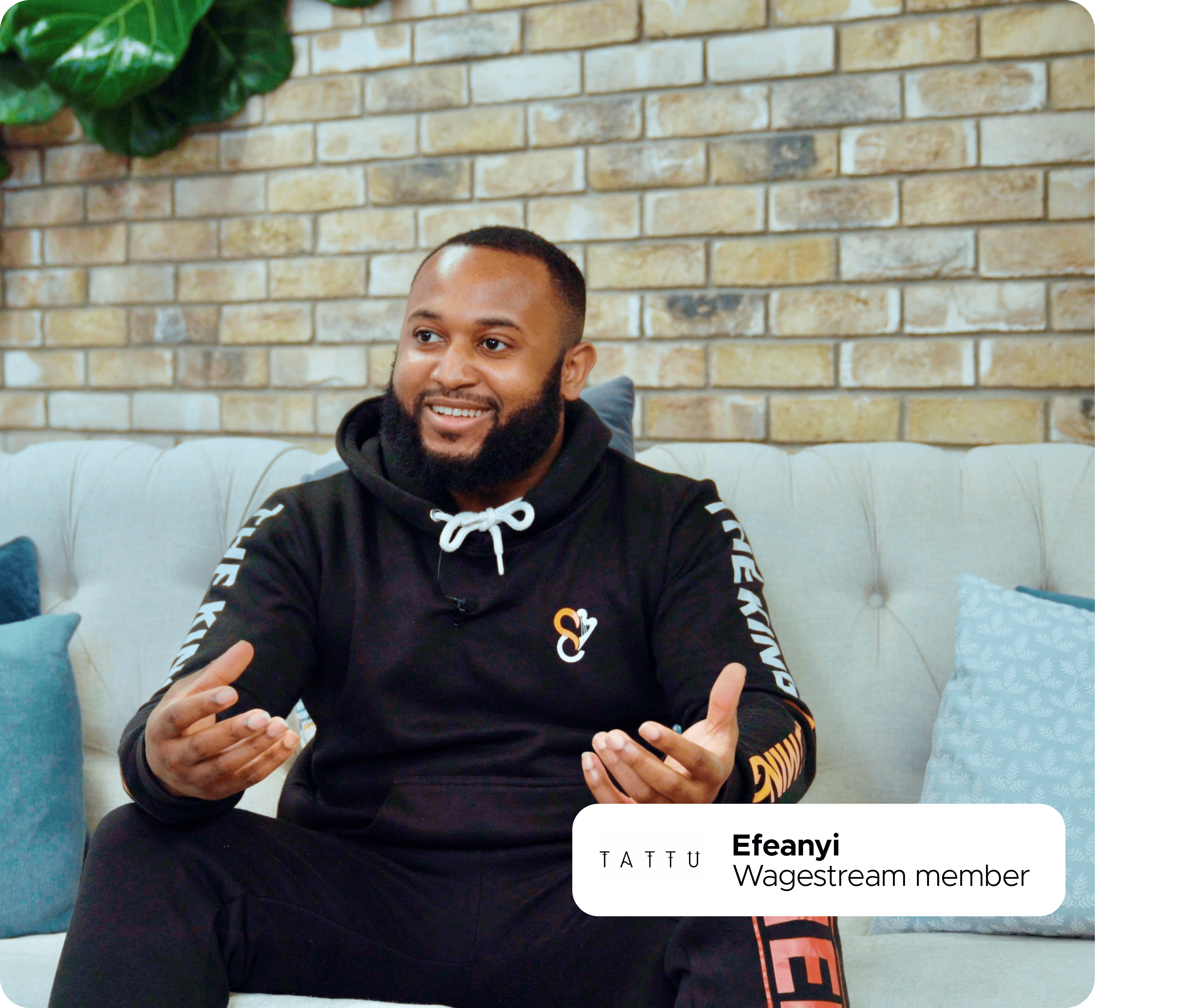 Efeanyi, Wagestream member, sits on a couch and smiles while speaking.
