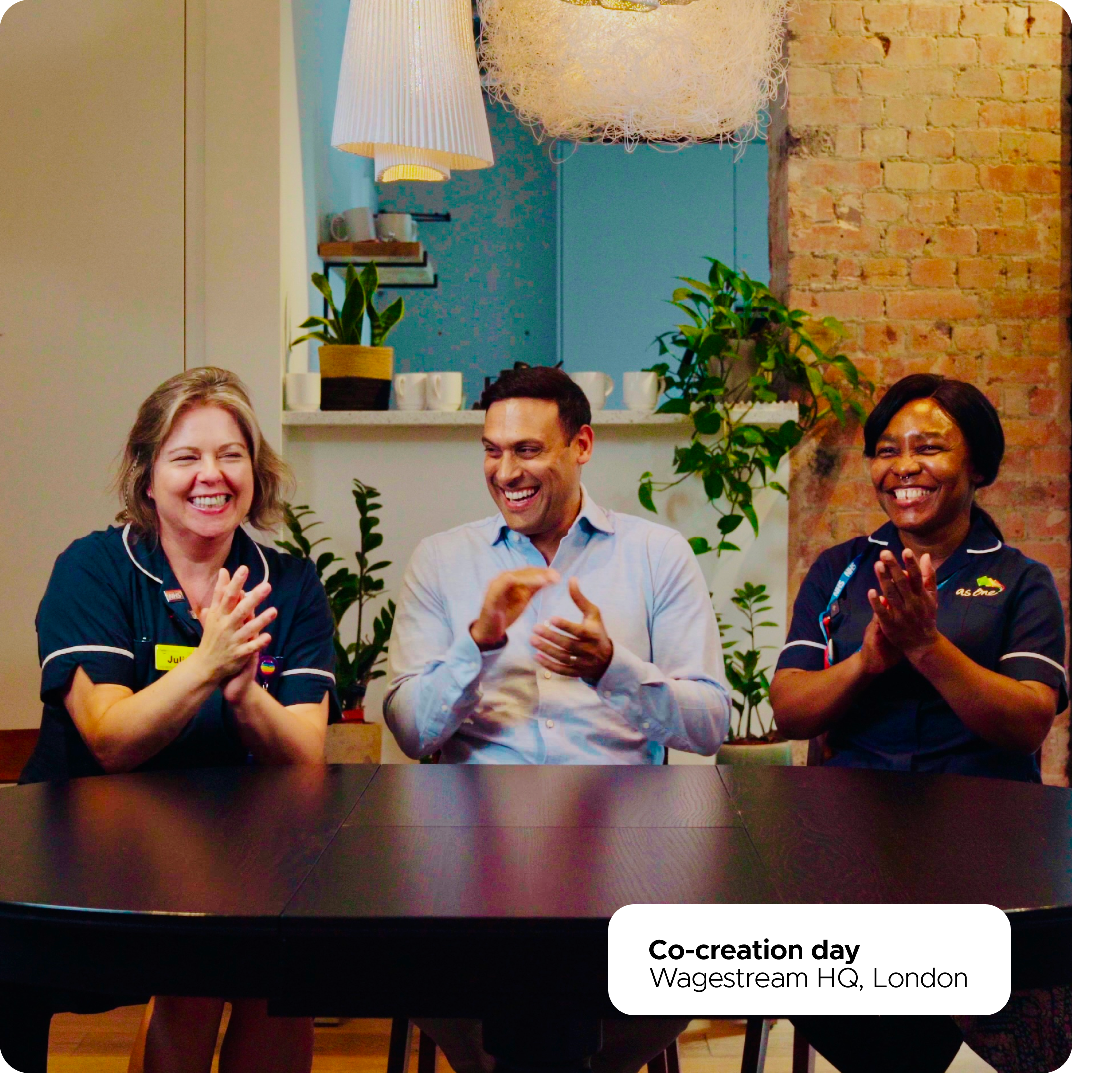 Three diverse Wagestream employees smiling and clapping during a co-creation day at the London HQ.
