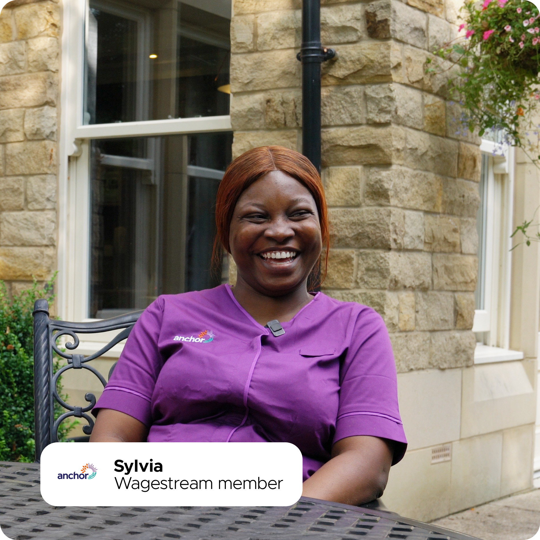 Smiling Sylvia, a Wagestream member, sits outside in a purple Anchor uniform.
