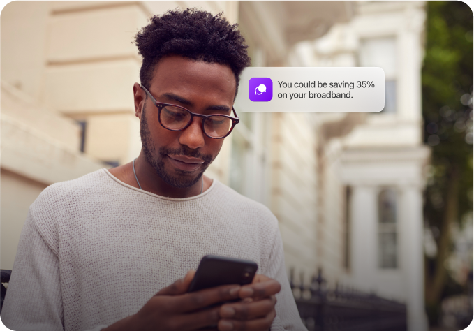 Man using smartphone, notification stating potential broadband savings.
