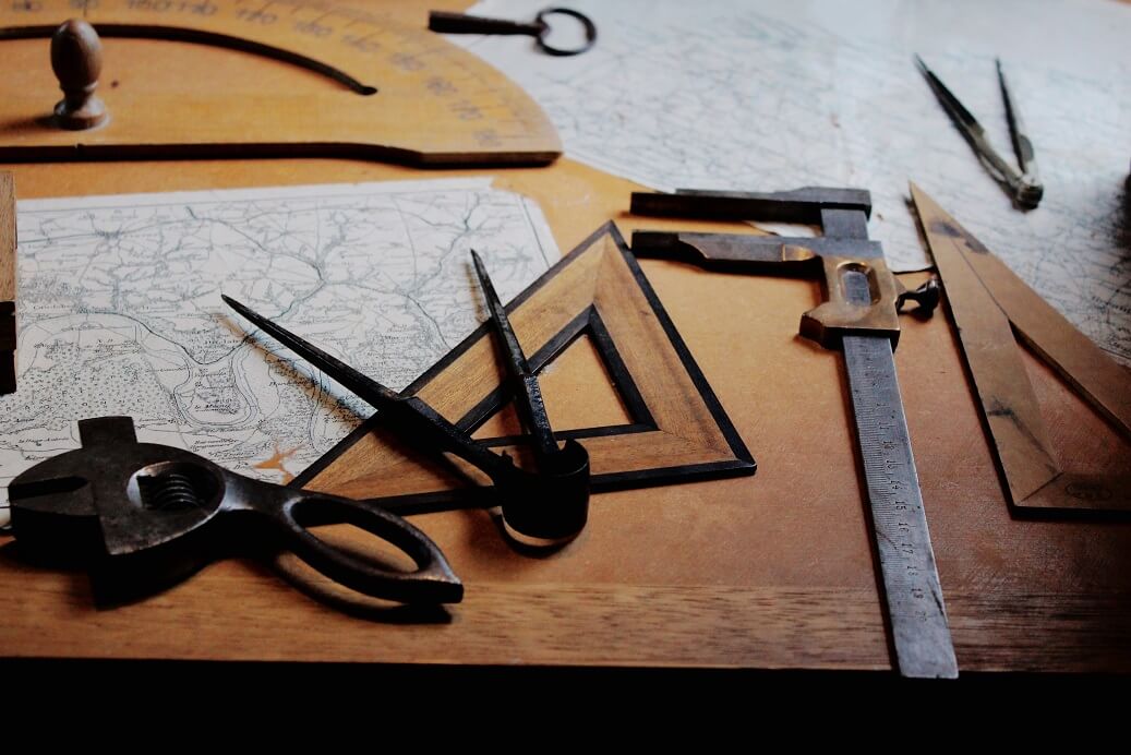 Antique drafting tools and map on a wooden table.
