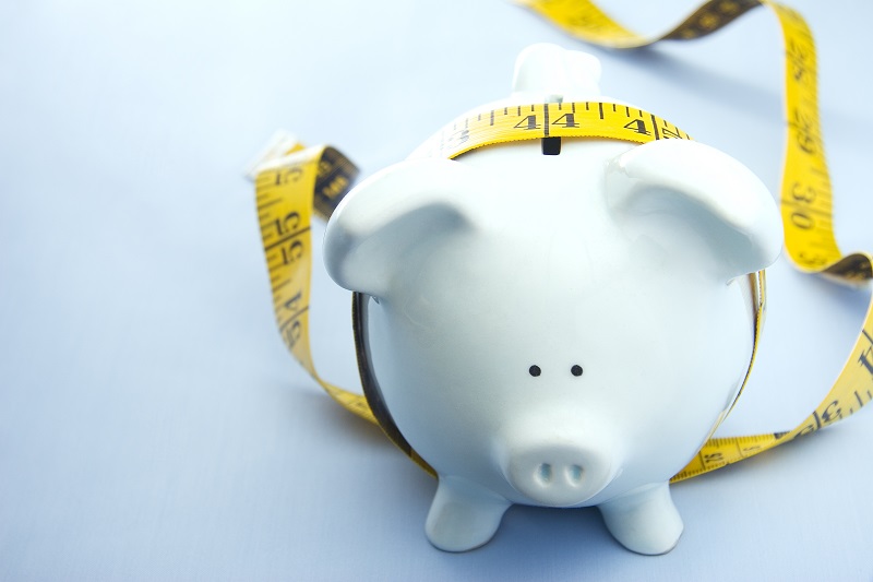 Piggy bank encircled by a measuring tape, symbolizing financial budgeting and saving.
