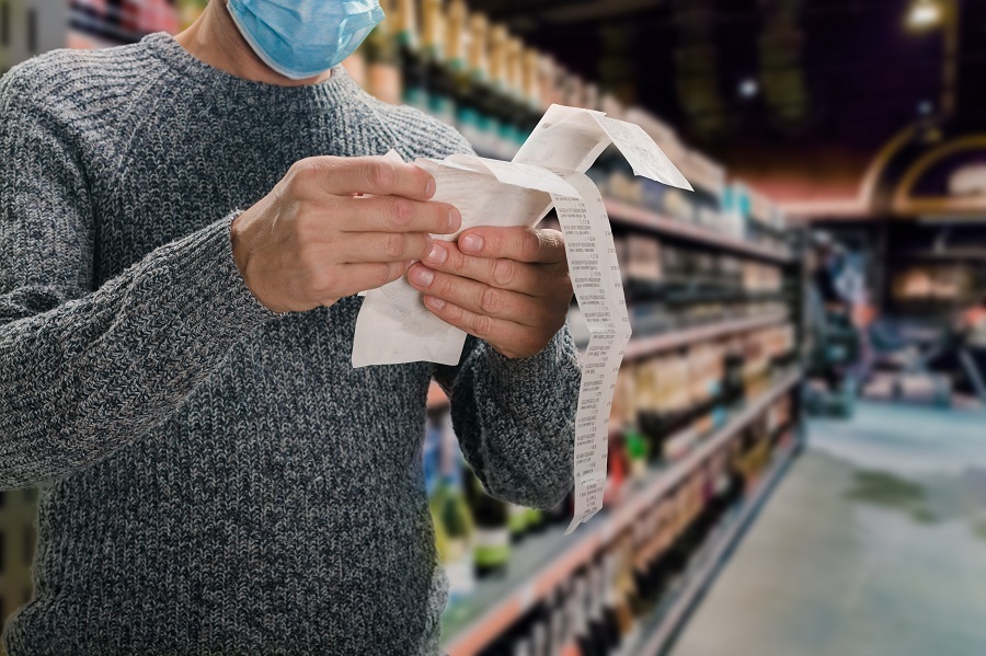 Person wearing a face mask reviewing a grocery receipt in a store.
