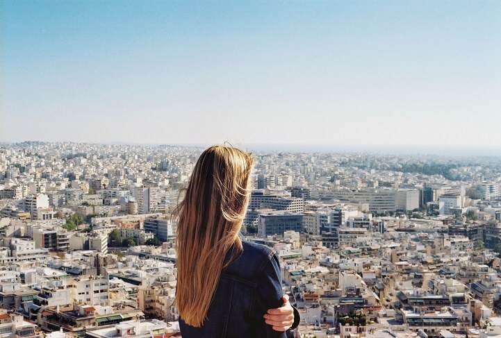 Woman with long hair looking out over a sprawling city landscape.
