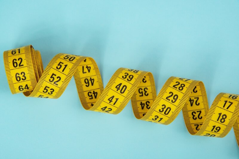 Yellow measuring tape curled on a light blue background.
