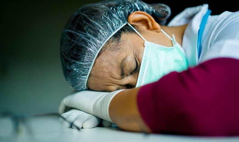 Exhausted healthcare worker sleeping at work, face down on a table.

